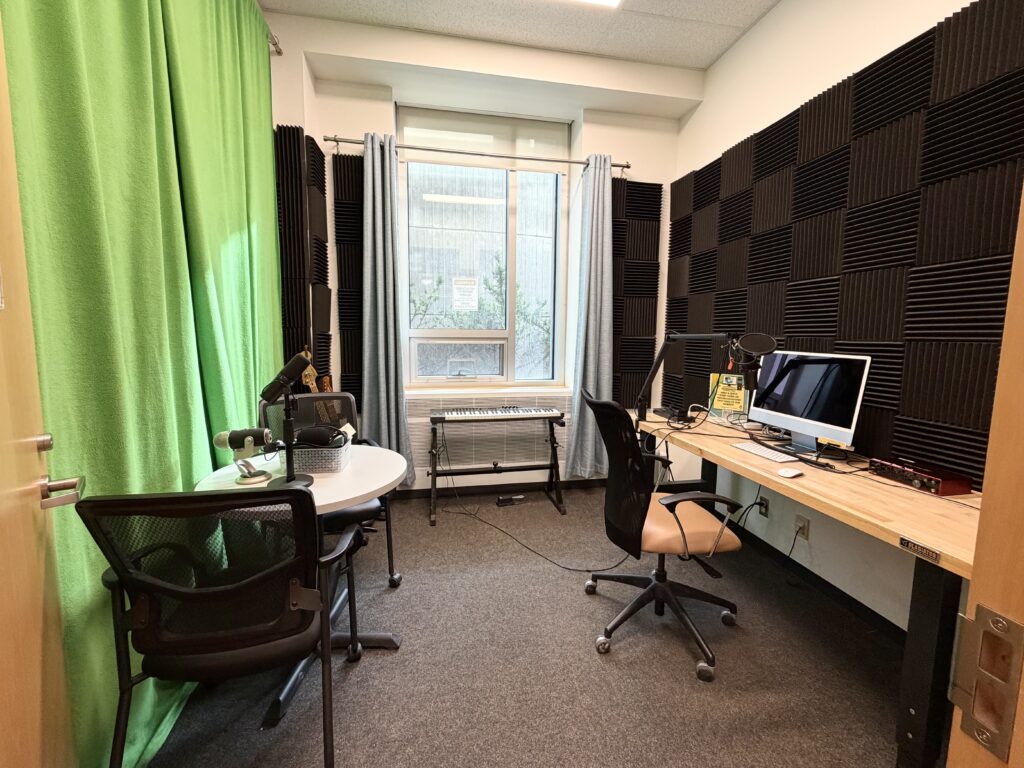 The Makerspace recording studio, equipped with podcast microphones, a green screen, acoustic foam walls and an iMac for editing. The room is available to any student during open hours and connects directly to the audio storytelling possibilities the space enables. (Singh, 2026)